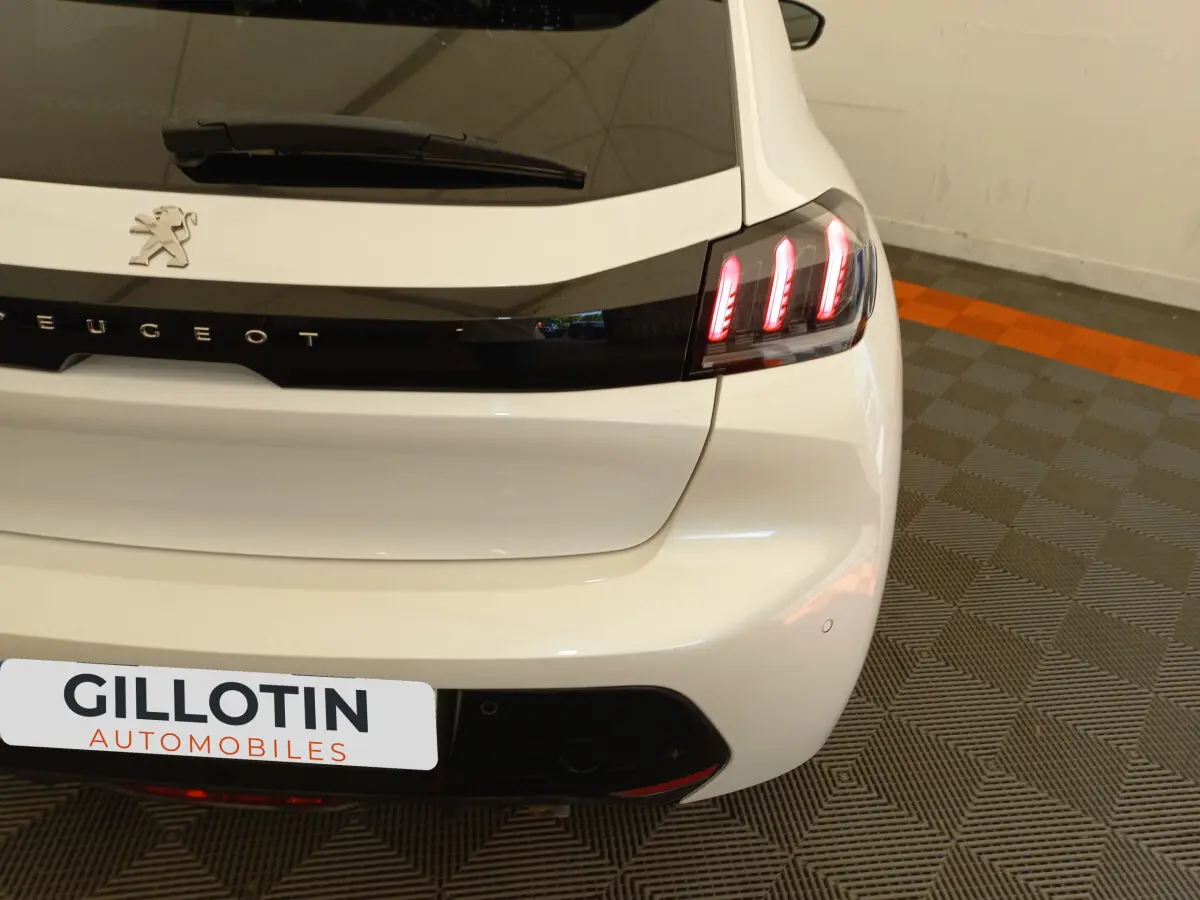 Vue arrière droite d'une Peugeot 208 blanche avec feux arrière LED et logo lion sur le hayon.