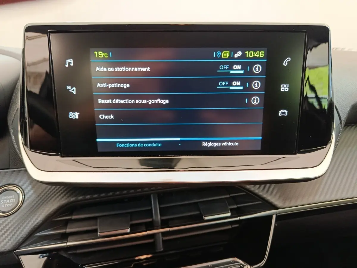 Écran tactile central affichant les réglages d’aide au stationnement et d’anti-patinage dans un Peugeot 208 électrique blanc.