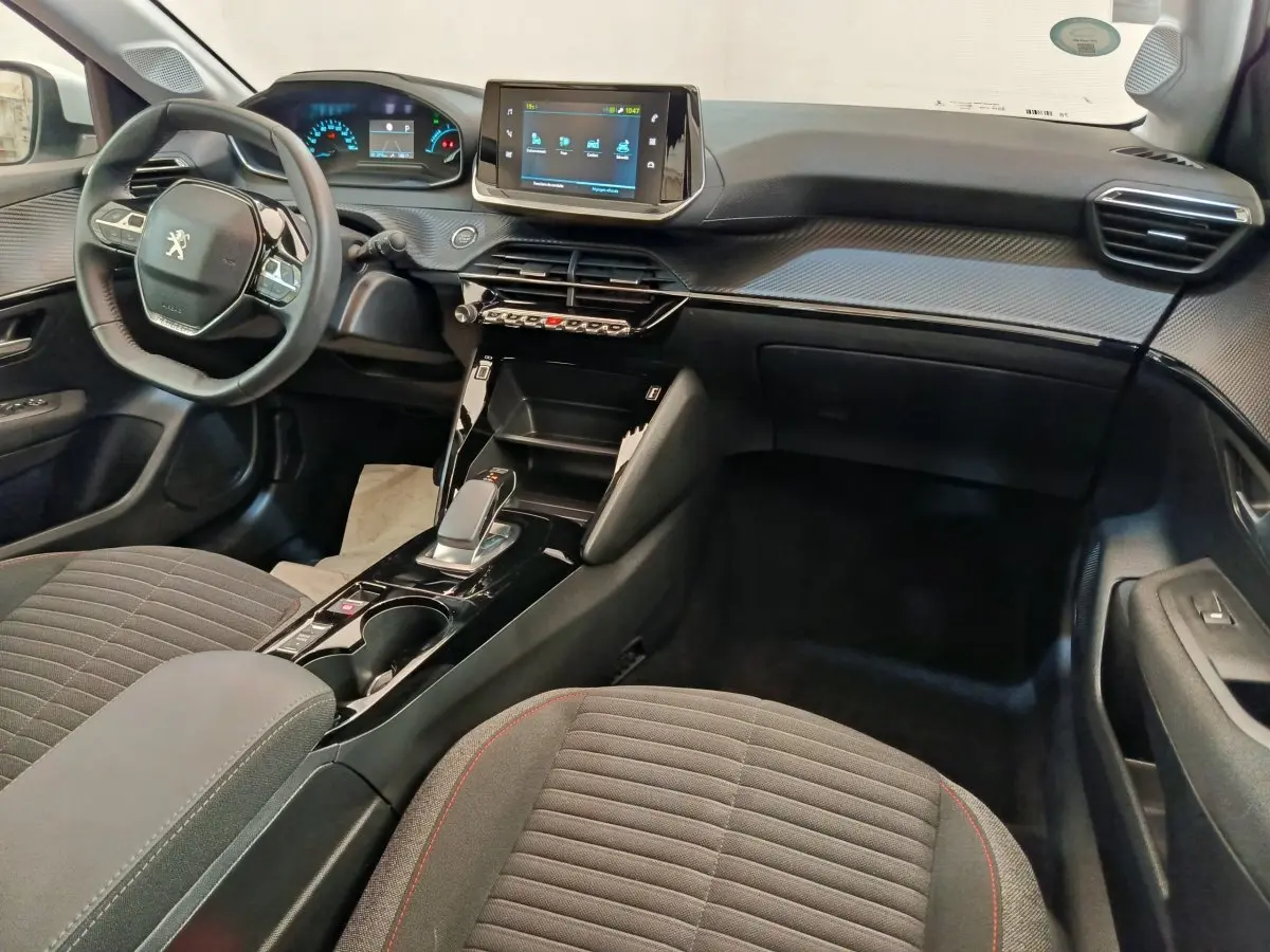Intérieur de la Peugeot 208 électrique 2021 vu côté passager, tableau de bord noir avec écran tactile central.