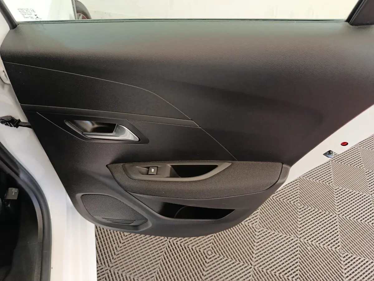 Vue rapprochée de la porte arrière gauche noire avec poignée argentée d'une Peugeot 208 électrique blanche.