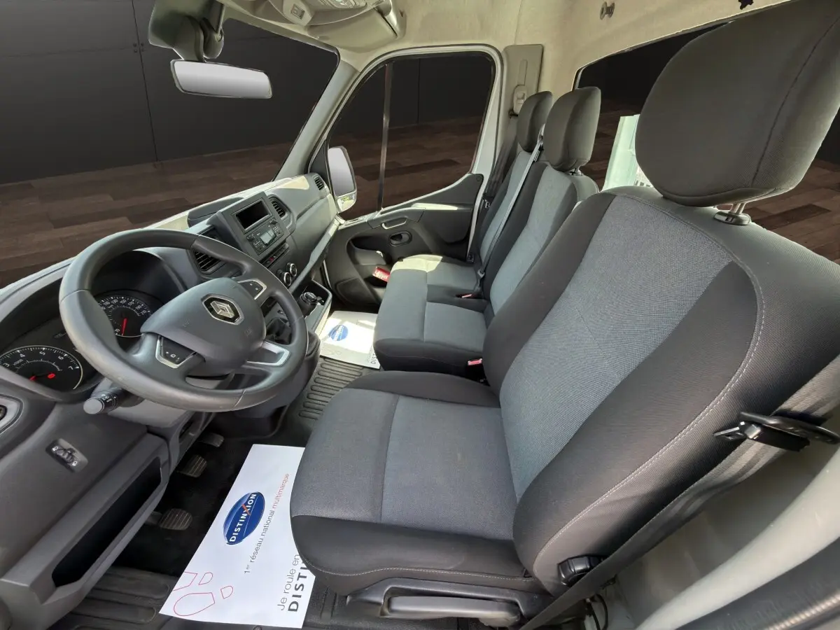 Vue intérieure côté conducteur du Renault Master 2024, sièges gris et tableau de bord noir avec volant réglable.
