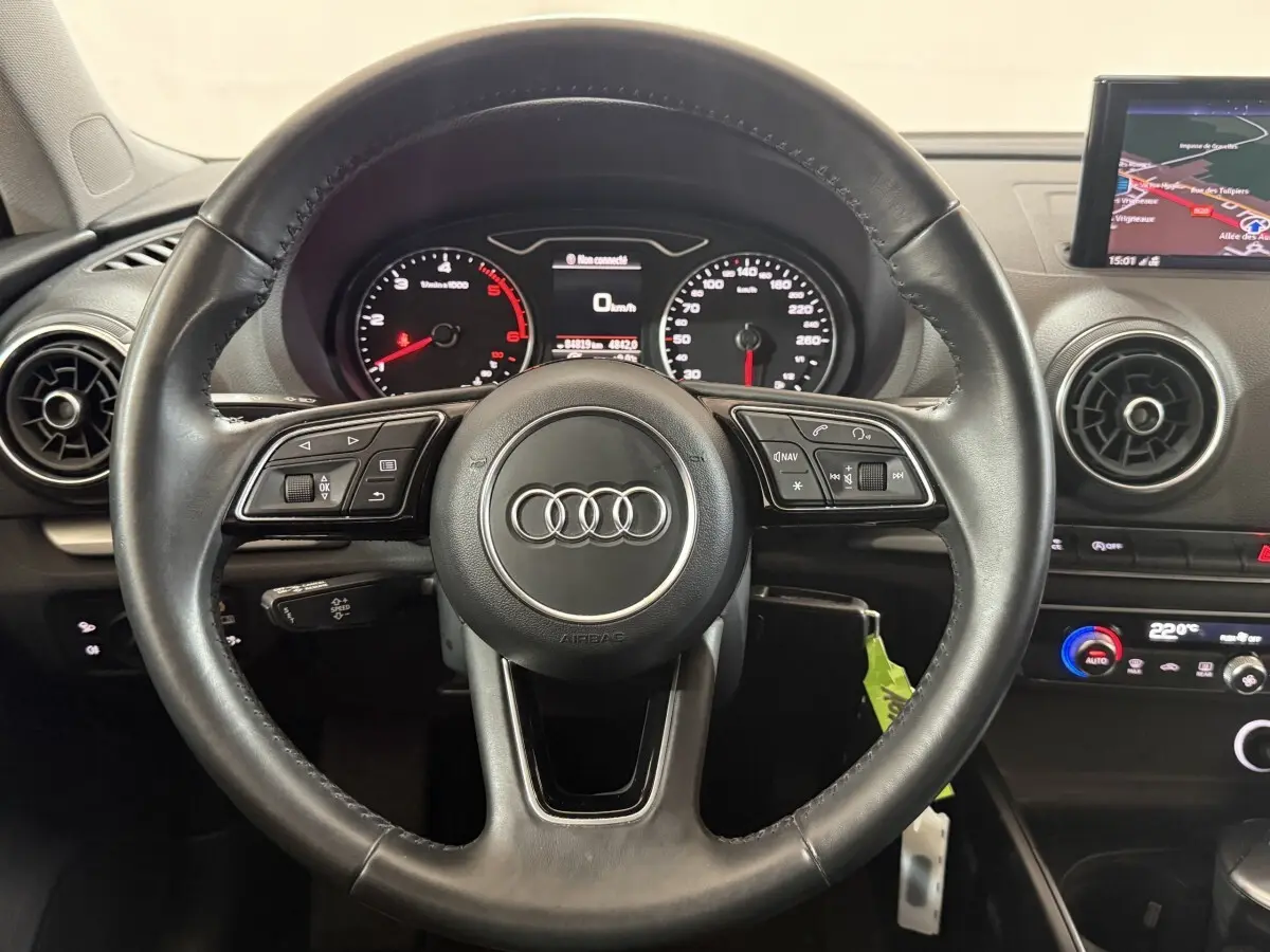 Vue centrée sur le volant cuir noir d'une Audi A3 2018 avec tableau de bord et écran de navigation visible.