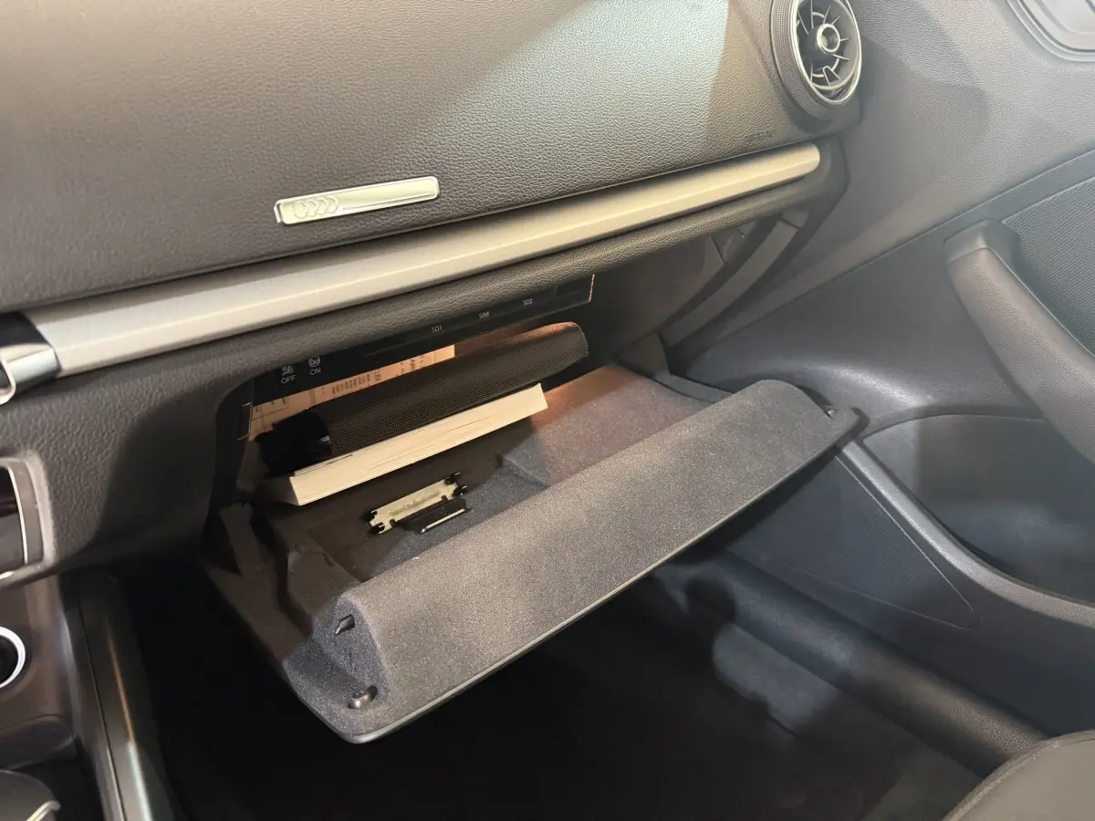 Gros plan sur la boîte à gants ouverte de l'Audi A3 2.0 TDI 150 Business Line, intérieur noir.