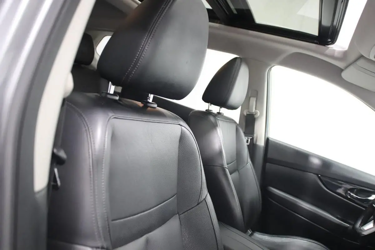 Vue intérieure avant du Nissan X-TRAIL 1.7 D 150 avec sièges cuir noirs et toit ouvrant panoramique ouvert.