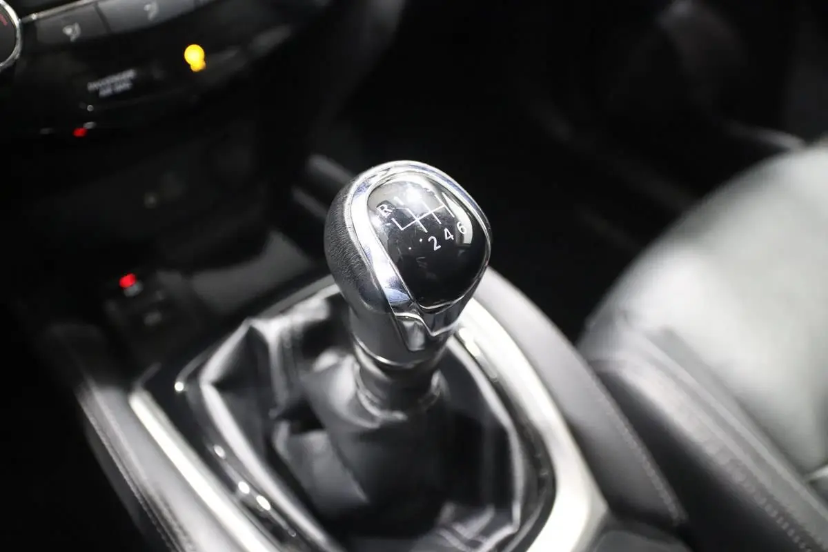 Gros plan sur le levier de vitesses manuel noir et chrome du Nissan X-Trail 1.7 D gris métallisé, intérieur cuir noir.