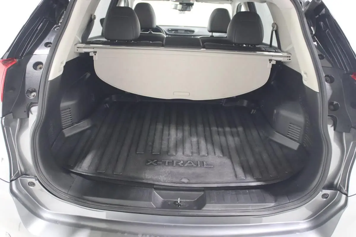 Coffre ouvert d'un Nissan X-Trail gris métallisé, vue arrière montrant le tapis de coffre avec logo X-TRAIL.