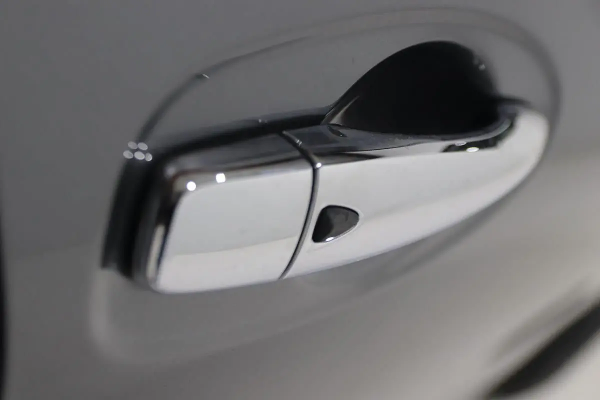 Poignée de porte chromée en gros plan sur Nissan X-TRAIL gris métallisé, côté droit du véhicule.