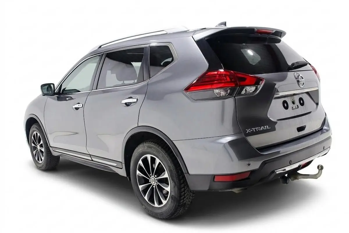 Vue 3/4 arrière droite d'un Nissan X-Trail gris métallisé avec attelage et toit ouvrant visible.