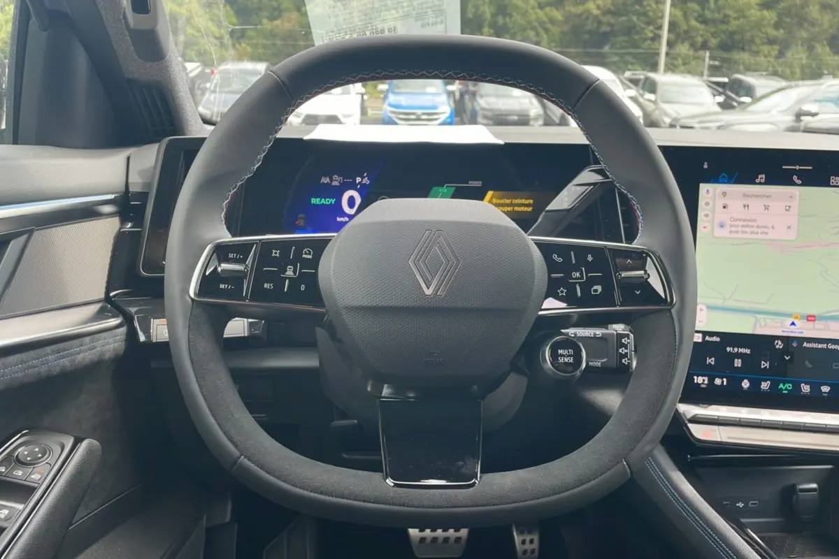 Vue intérieure centrée sur le volant cuir multifonctions du Renault Austral gris schiste avec tableau de bord digital et écran tactile.