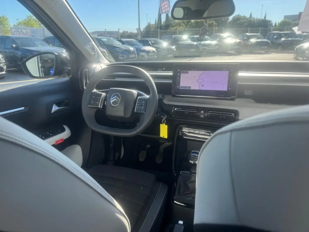 Vue intérieure avant de la Citroën C3 gris 2025, montrant le volant, écran tactile et levier de vitesse manuel.