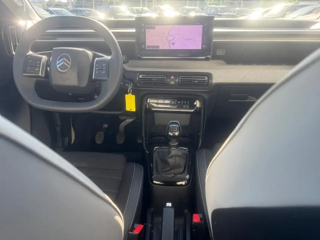 Vue intérieure avant de la Citroën C3 gris 2025, volant multifonction, écran tactile et levier de vitesse manuel visible.
