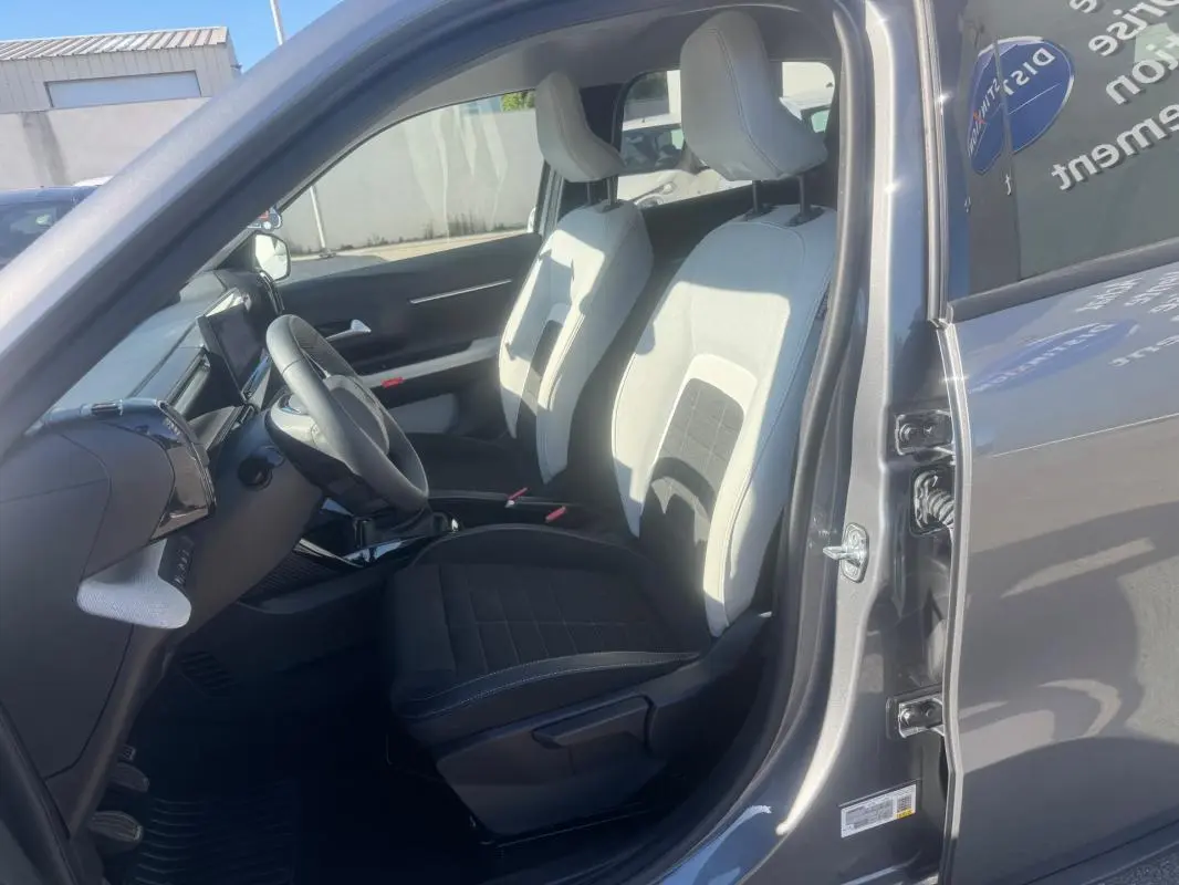 Vue intérieure côté conducteur de la Citroën C3 gris 2025, montrant les sièges bicolores et le volant avec commandes intégrées.