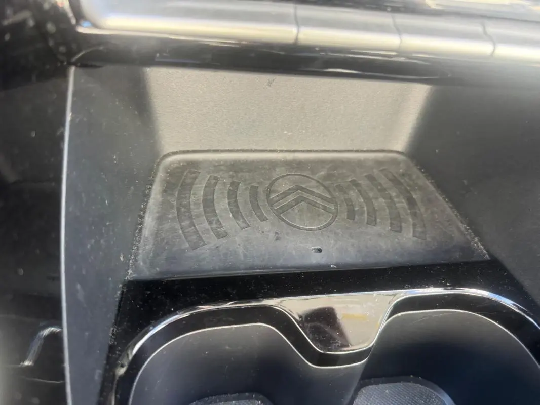Gros plan sur le compartiment de recharge sans fil avec logo Citroën, intérieur noir de la C3 Turbo 2025.