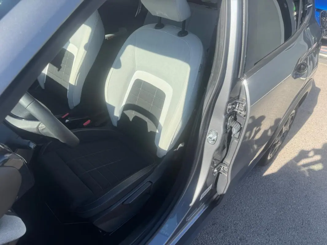 Vue intérieure côté conducteur d'une Citroën C3 gris 2025, montrant le siège avant clair et foncé avec portière ouverte.