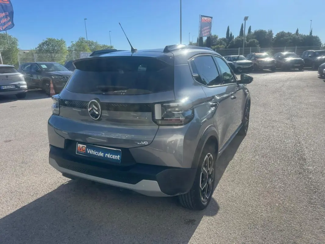 Vue 3/4 arrière droite d'une Citroën C3 Turbo 100 ch gris avec jantes alliage 17 pouces et barres de toit visibles.