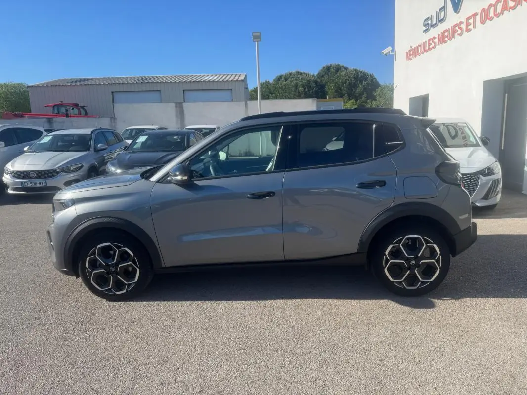 Vue de profil côté gauche d'une Citroën C3 gris 2025 avec jantes alliage 17 pouces et barres de toit noires.