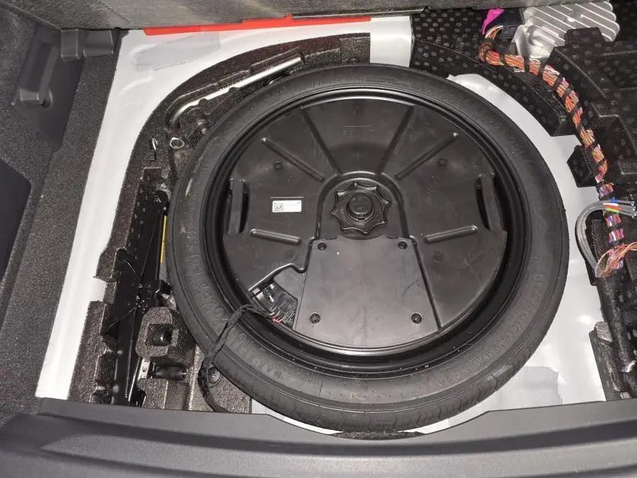 Vue rapprochée de la roue de secours compacte noire dans le coffre blanc du CUPRA Formentor 2025.