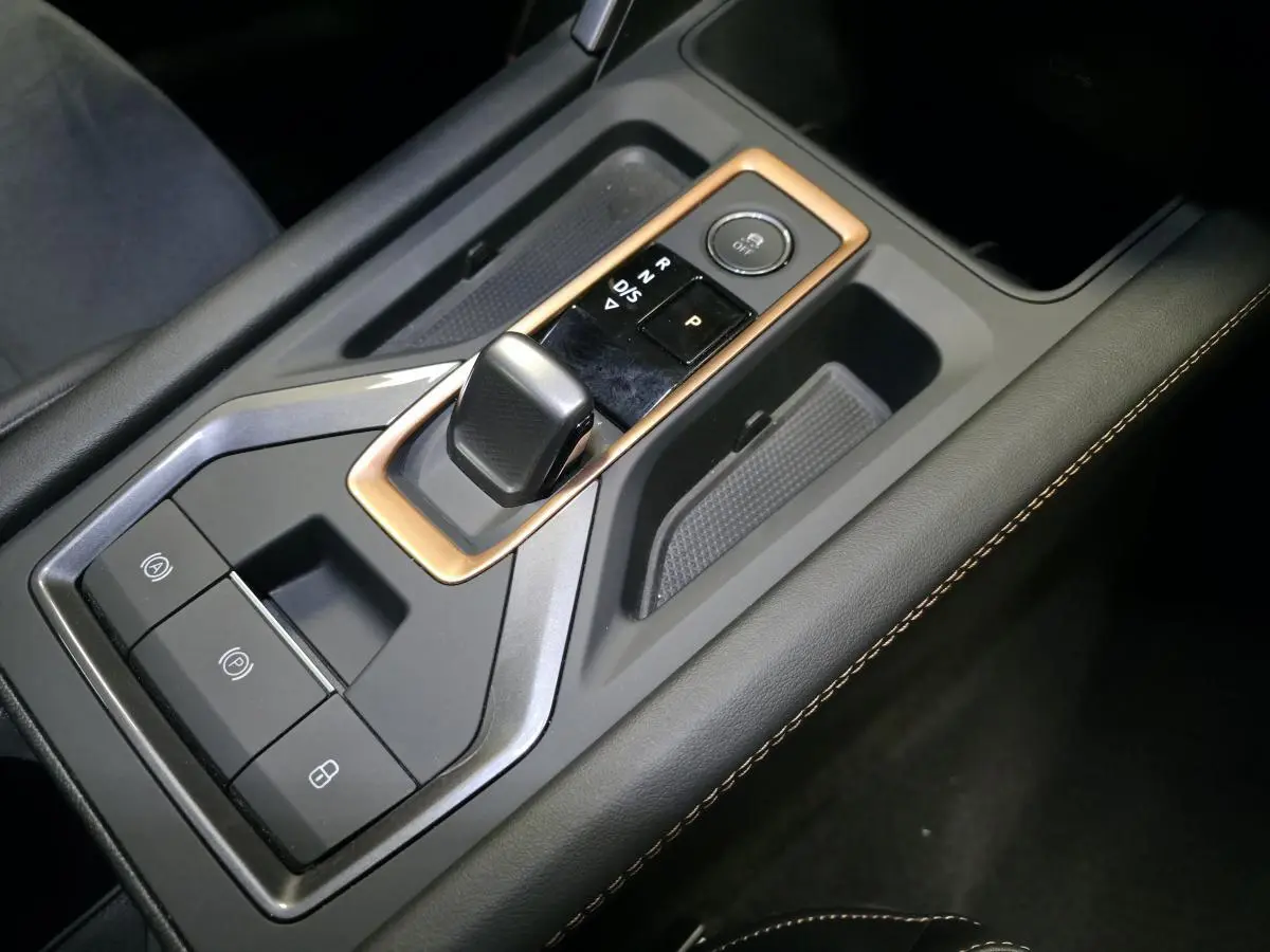 Gros plan sur la console centrale du CUPRA Formentor blanc avec levier de vitesses DSG et surpiqûres cuivrées.