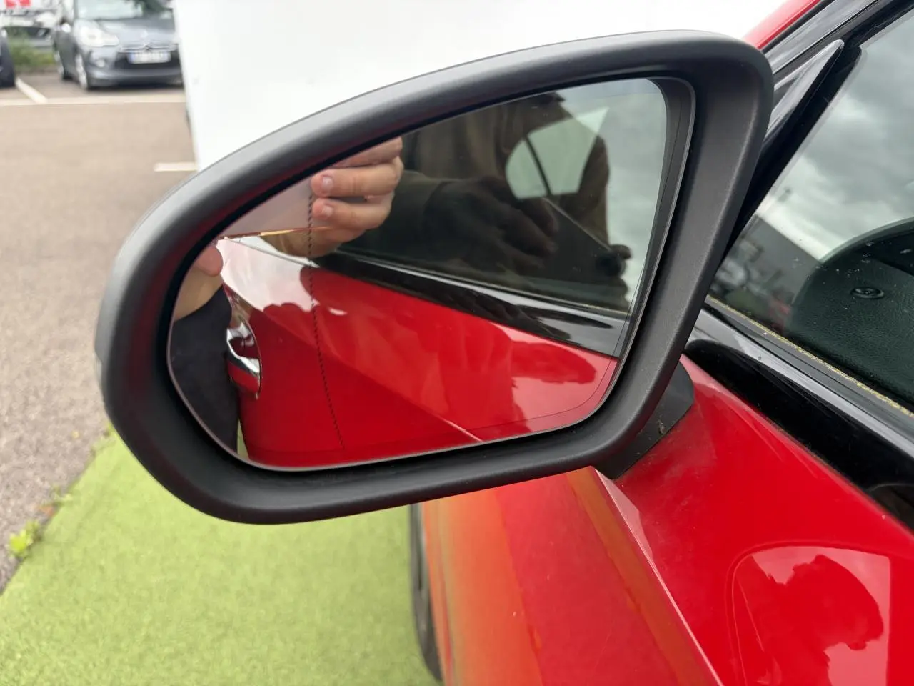 Rétroviseur extérieur côté gauche d’une Mercedes Classe A rouge, avec carrosserie brillante et contours noirs.
