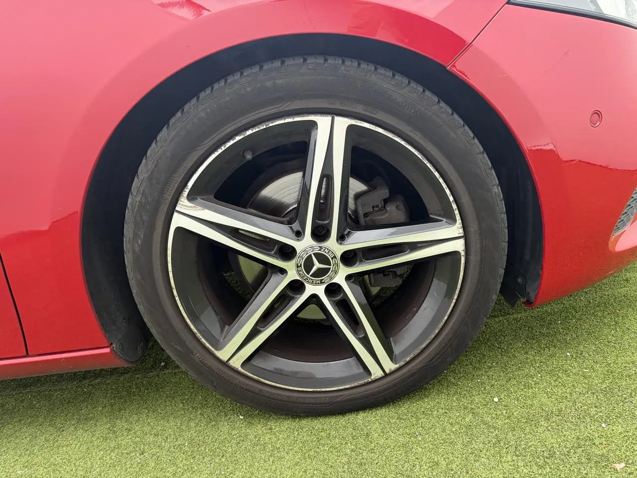 Gros plan sur la roue avant gauche rouge d'une Mercedes Classe A avec jante alliage 5 branches noire et argent.