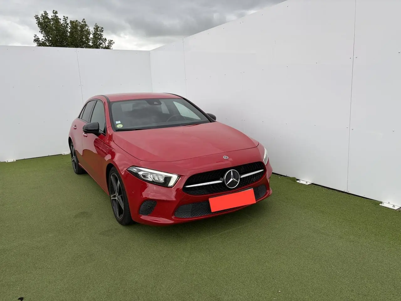 Mercedes Classe A IV 180 D Progressive Line rouge vue en 3/4 avant avec jantes alliage noires et calandre diamant.