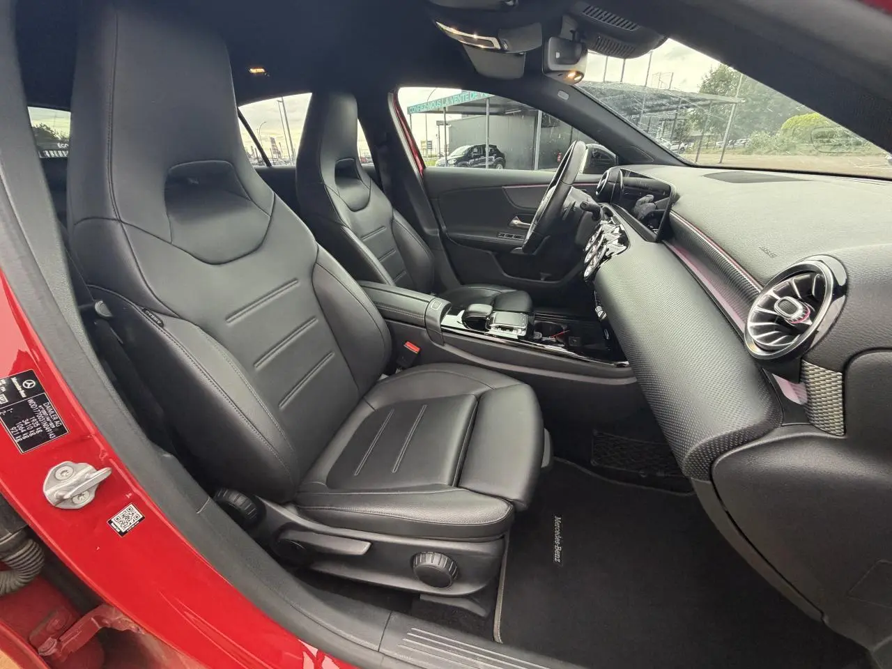 Intérieur avant droit d'une Mercedes Classe A rouge 2019 avec sièges cuir noir et tableau de bord moderne.
