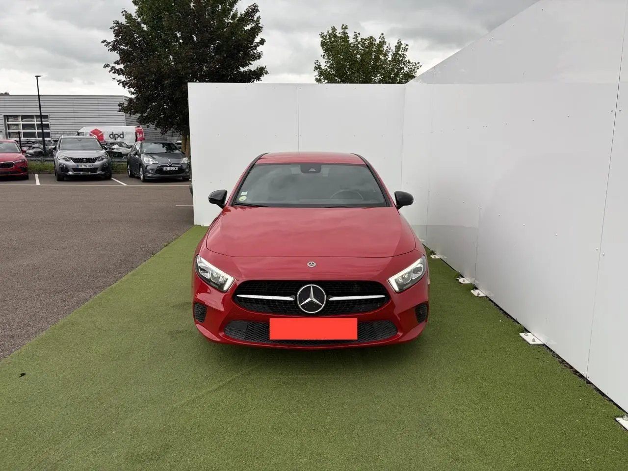 Vue avant d'une Mercedes Classe A IV 180 d Progressive Line rouge, avec calandre diamant et logo central visible.