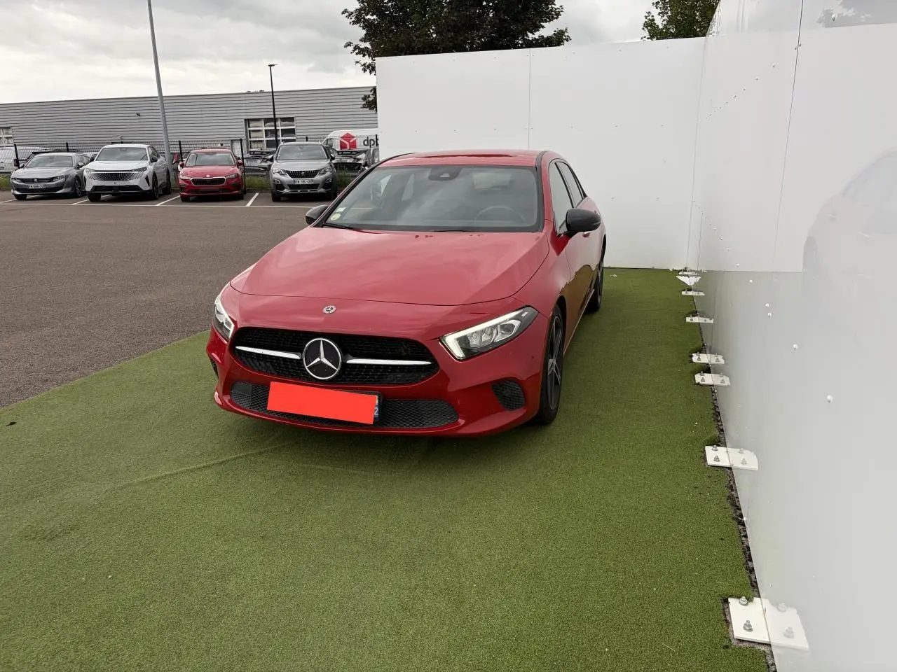 Mercedes Classe A rouge vue de face en léger angle droit, avec calandre noire et logo étoile bien visible.
