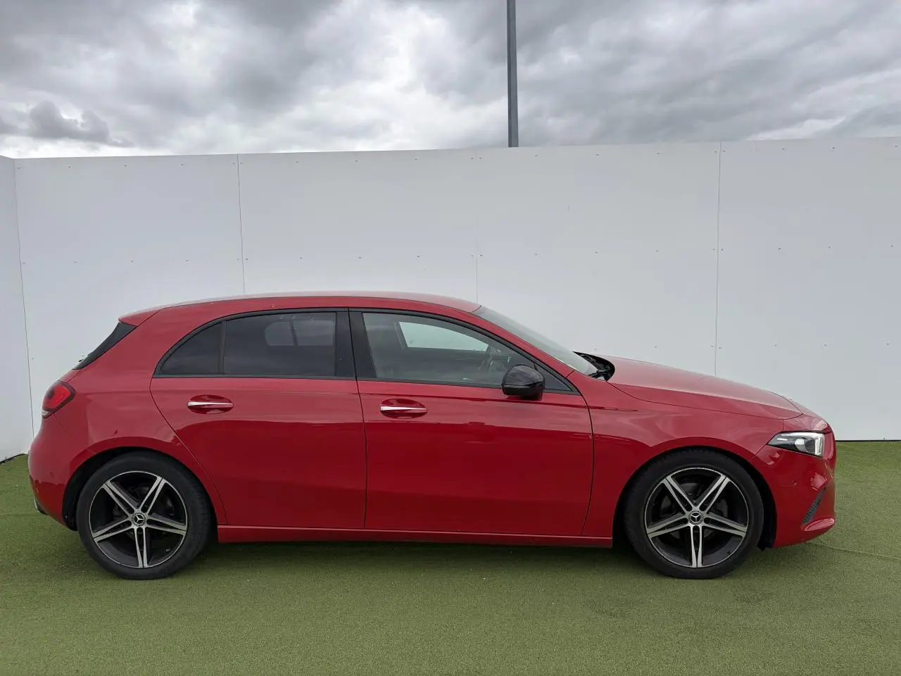 Vue de profil côté gauche d'une Mercedes Classe A rouge avec jantes alliage sport à 5 branches.