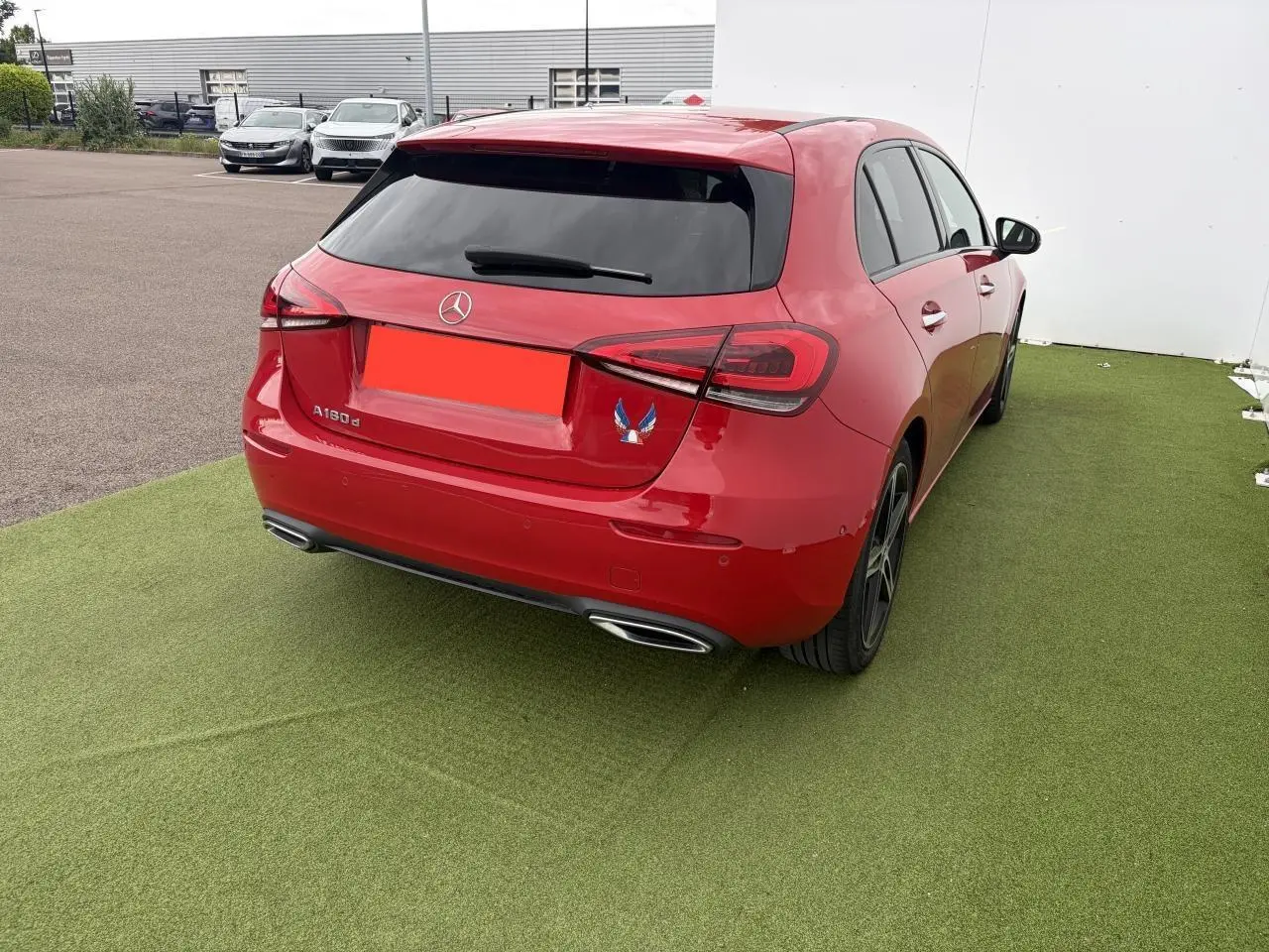 Vue 3/4 arrière droite d'une Mercedes Classe A rouge avec vitres teintées et sorties d'échappement chromées.