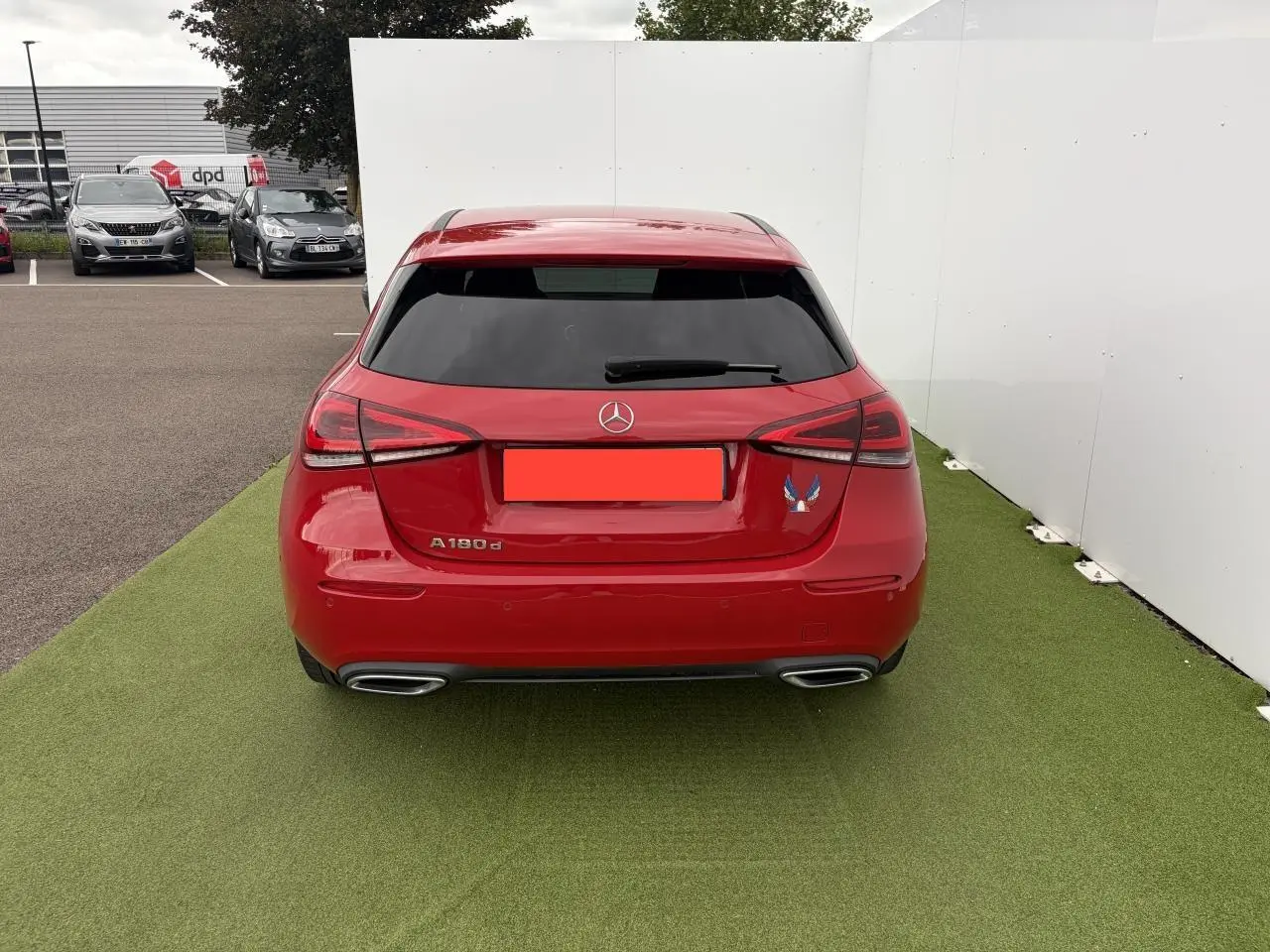 Vue arrière d'une Mercedes Classe A 180d rouge avec vitres teintées et doubles sorties d'échappement chromées.