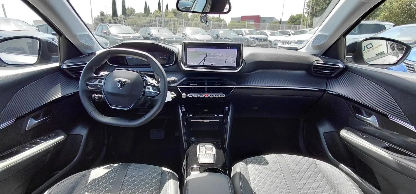 Intérieur de la Peugeot 208 gris, vue de face sur le tableau de bord avec écran tactile et volant multifonction.