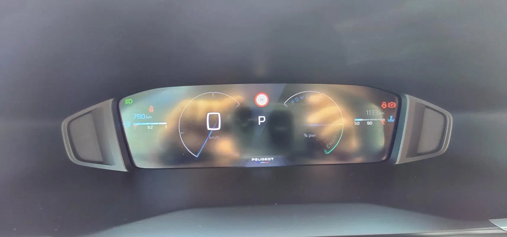Tableau de bord numérique de Peugeot 208 Hybrid 110 ch en vue frontale, affichant vitesse et autonomie.