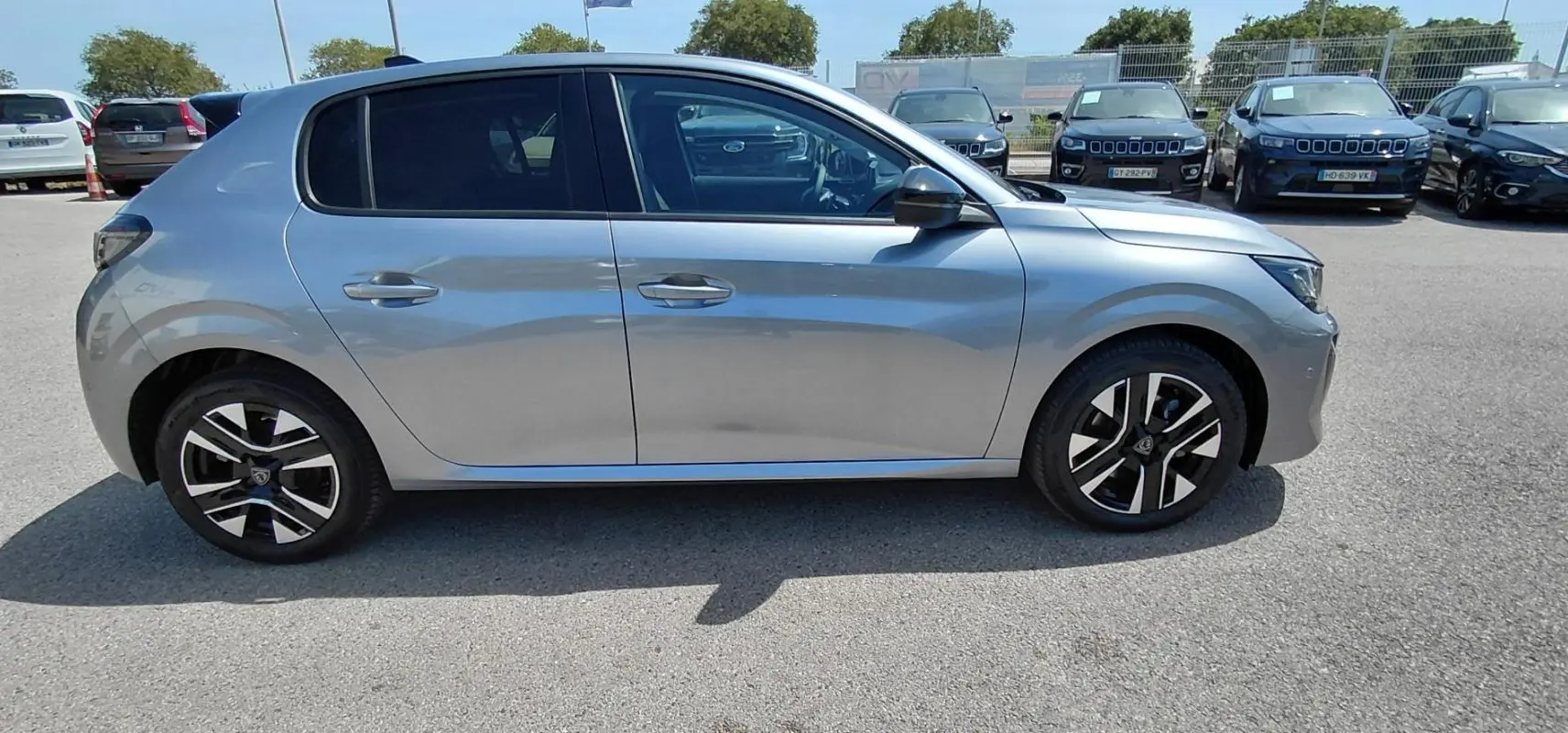 Peugeot 208 gris vue de profil côté gauche, avec jantes alliage noires et vitres teintées.