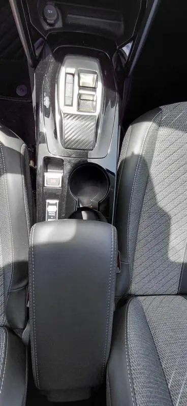 Vue plongeante sur la console centrale noire et les sièges gris du Peugeot 208 Hybrid 110 ch e-DCS6 Allure 2025.