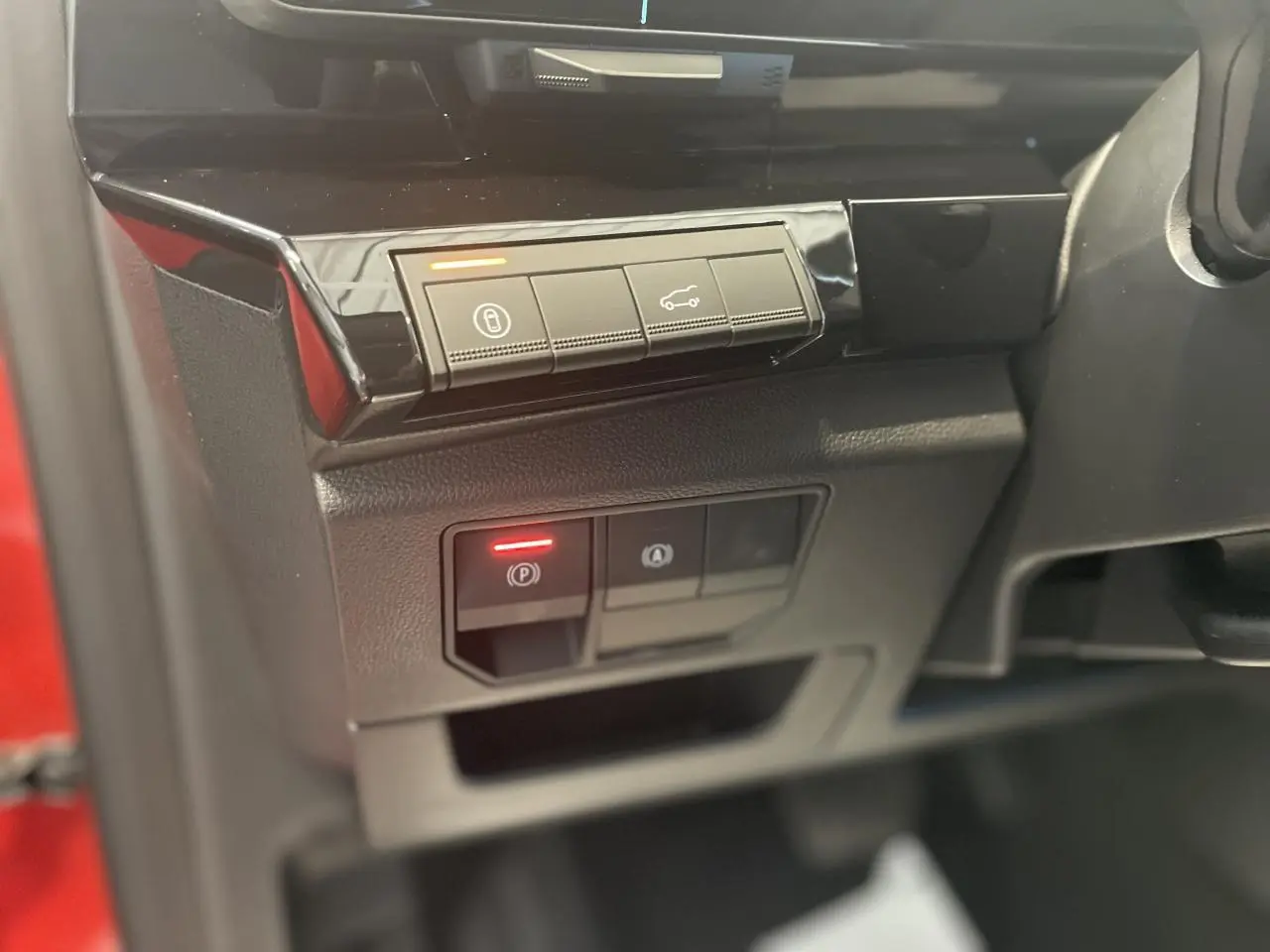 Gros plan sur les commandes du tableau de bord côté gauche d'une Renault Rafale rouge, avec bouton frein de parking activé.