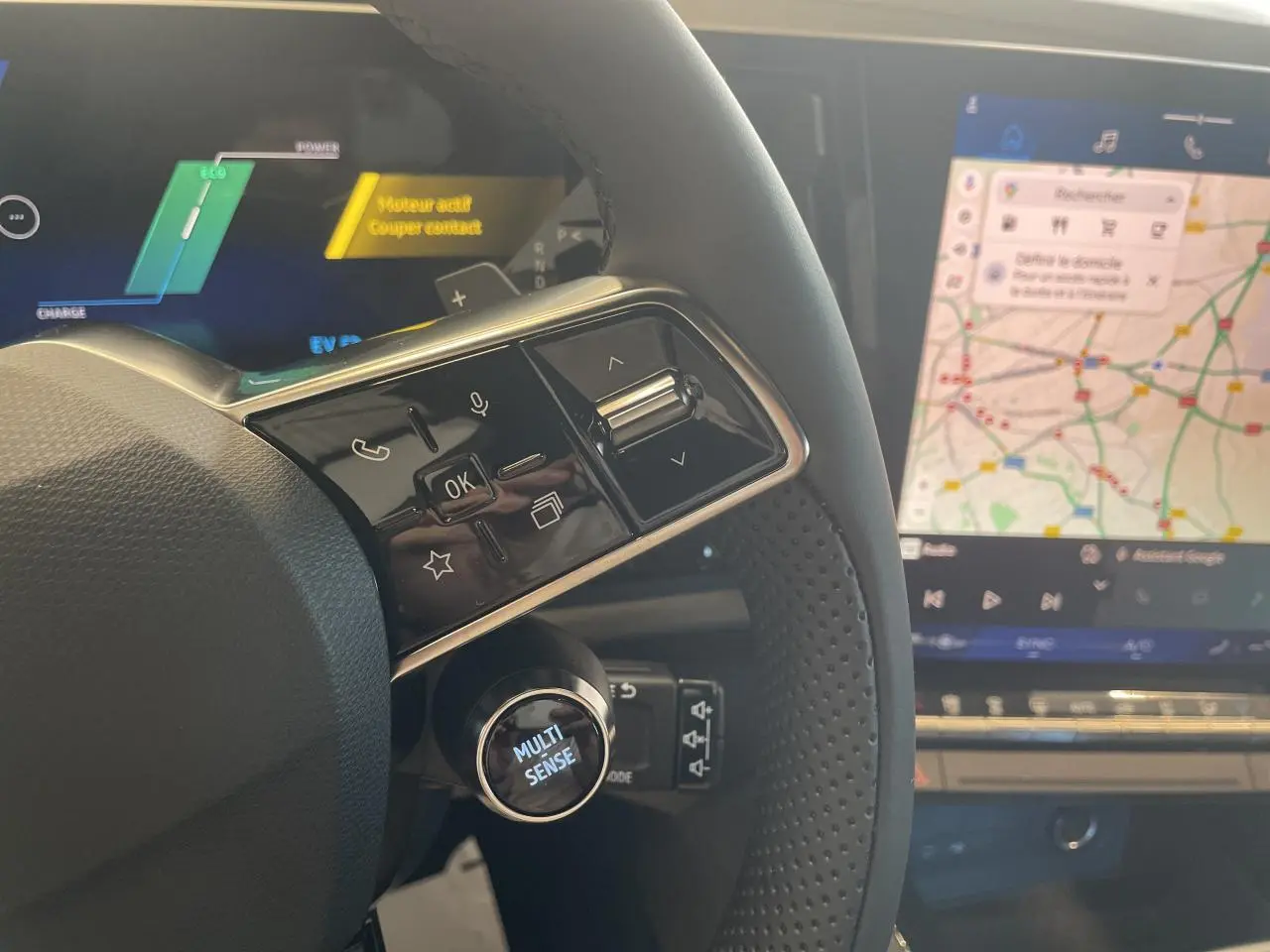Gros plan sur le volant textile refined et les commandes multifonctions du Renault Rafale 2025 avec écran tactile affichant la navigation.
