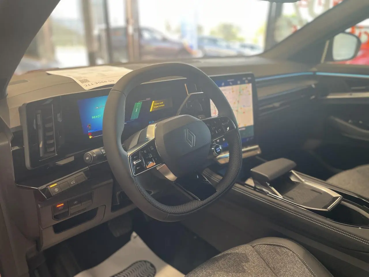 Intérieur Renault Rafale 2025 vu côté conducteur, volant compact avec logo Renault et écran tactile central lumineux.