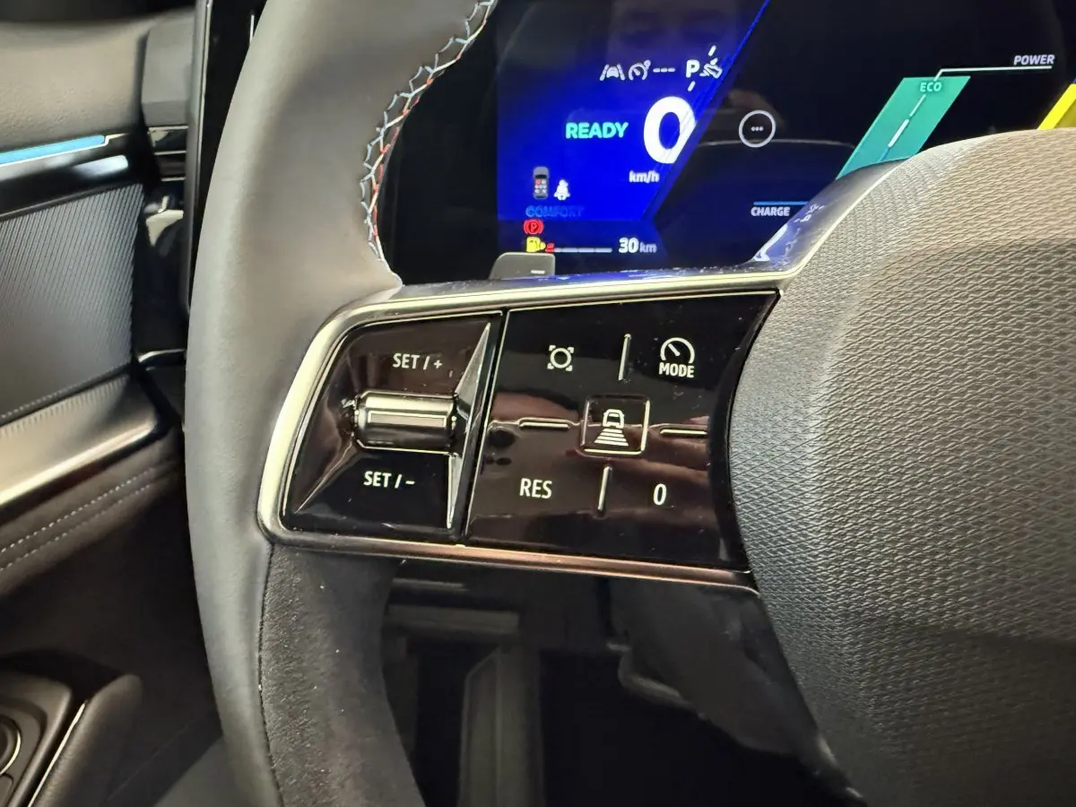 Gros plan sur le volant cuir avec commandes multifonctions et tableau de bord numérique bleu du Renault Espace esprit Alpine 2025.