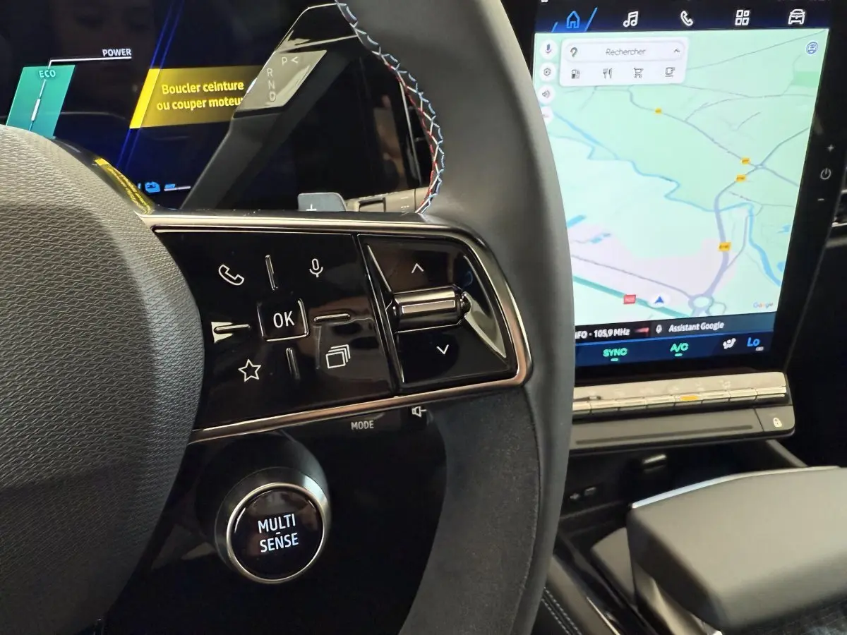 Gros plan sur le volant cuir et suede avec commandes multifonctions du Renault Espace esprit Alpine 2025, écran tactile de navigation visible.