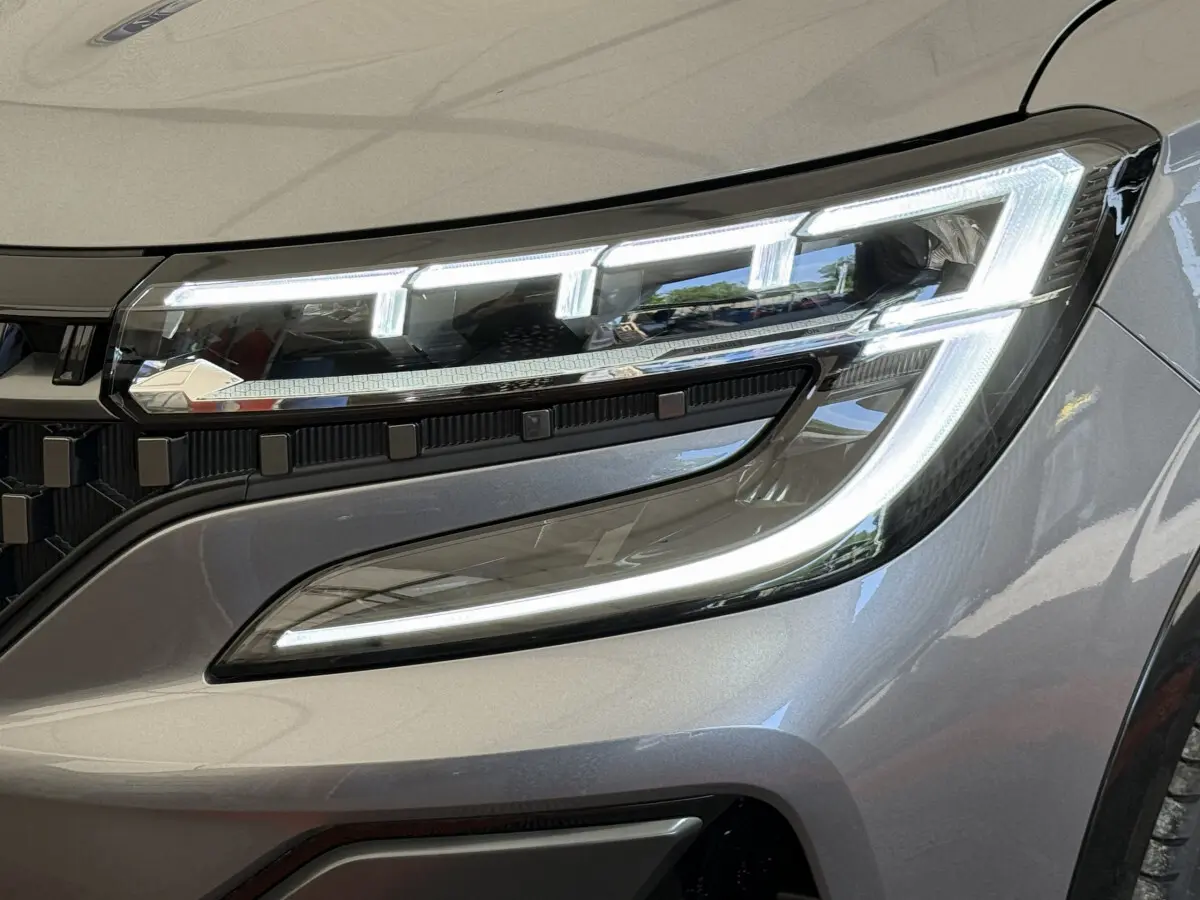 Gros plan sur le phare avant droit LED du Renault Espace esprit Alpine gris foncé, soulignant son design moderne et lumineux.
