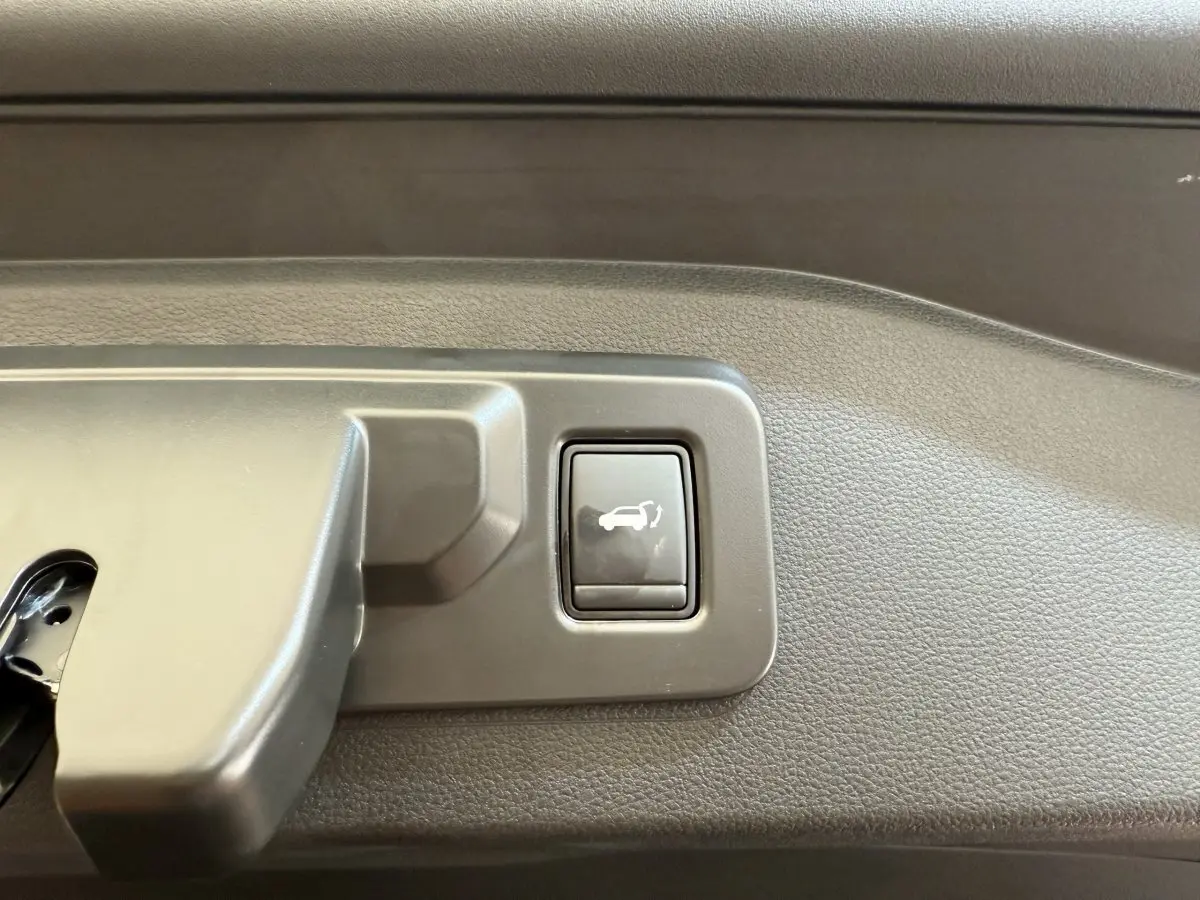 Gros plan sur le bouton d'ouverture électrique du coffre dans un Renault Espace gris foncé esprit Alpine 2025.