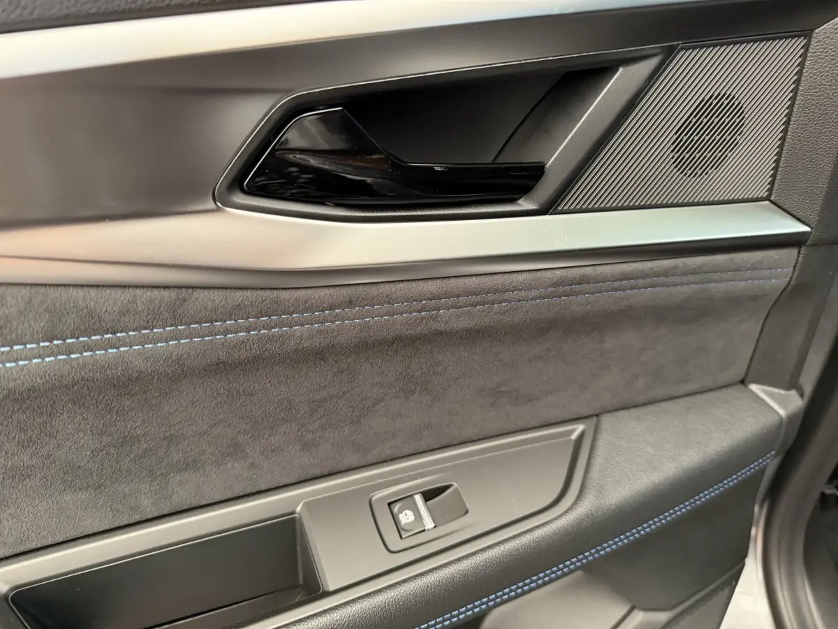 Gros plan sur la garniture intérieure côté droit de porte du Renault Espace gris foncé esprit Alpine avec surpiqûres bleues.