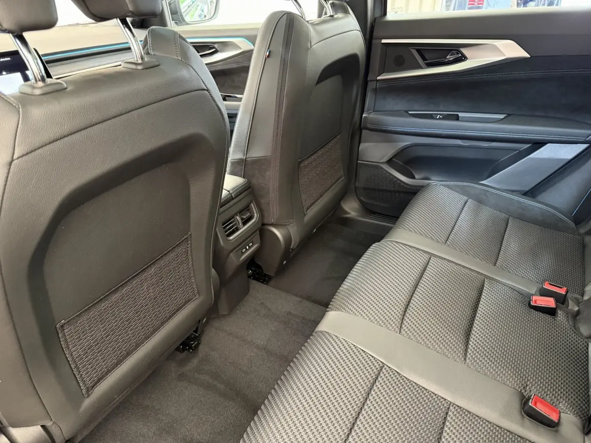Vue intérieure arrière côté droit du Renault Espace gris foncé, sièges en tissu et cuir noir avec ceintures rouges.