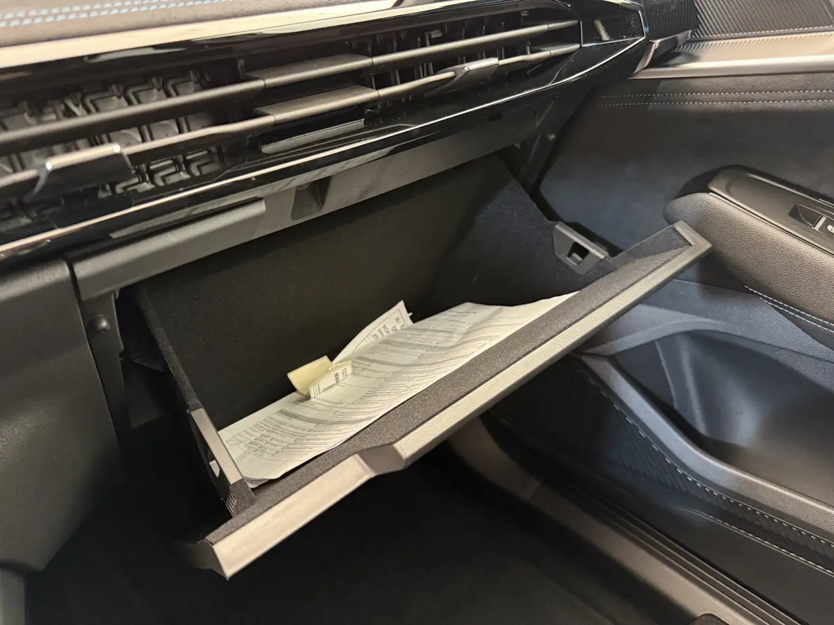Gros plan sur la boîte à gants ouverte côté passager du Renault Espace gris foncé esprit Alpine 2025 avec documents à l'intérieur.