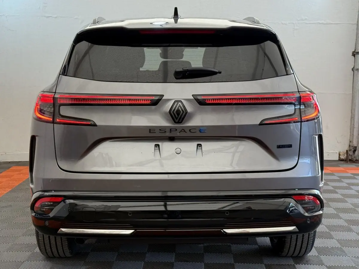 Vue arrière du Renault Espace gris foncé 2025 esprit Alpine hybride avec feux LED étirés et logo central visible.