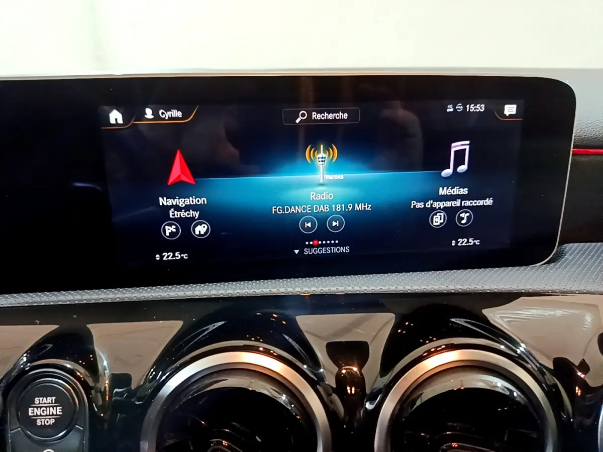 Écran tactile central affichant navigation et radio, avec commandes d’aération rondes dans l’habitacle d’une Mercedes Classe A noire.