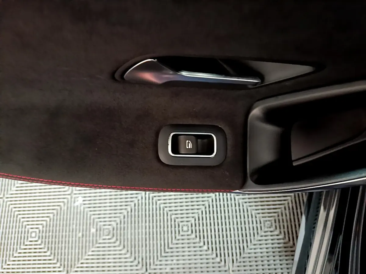 Gros plan sur la poignée intérieure et bouton de la portière côté gauche d’une Mercedes Classe A 180 AMG Line noire.