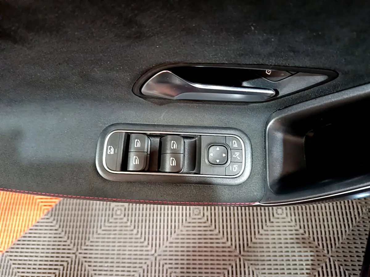 Commande des vitres et rétroviseurs sur la porte côté gauche d'une Mercedes Classe A 180 AMG Line noire, intérieur noir avec surpiqûres rouges.