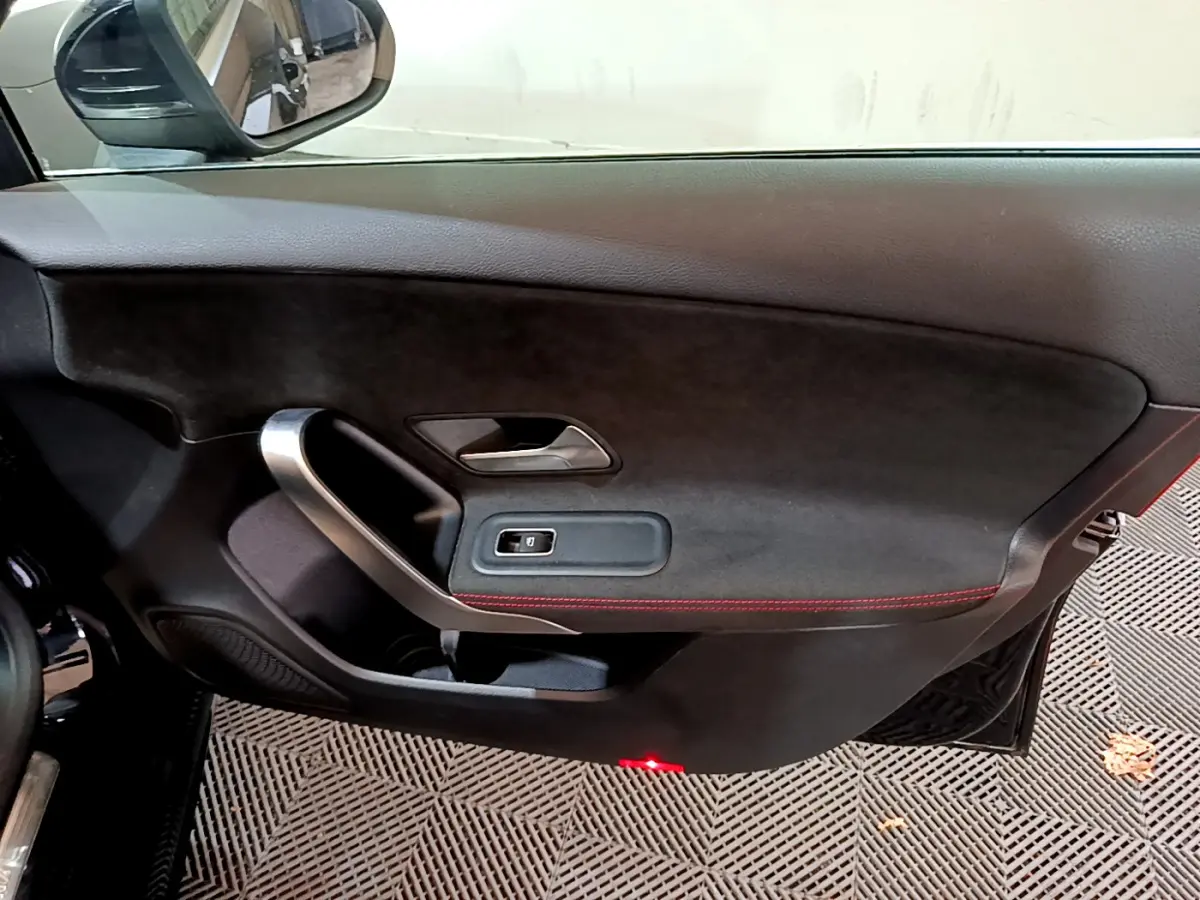 Intérieur côté gauche de porte Mercedes Classe A 180 AMG Line noire avec surpiqûres rouges et poignée alu.